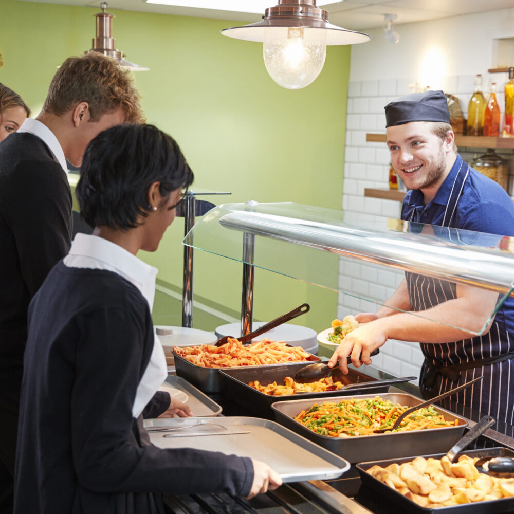 Teenage Students Being Served Meal In School Canteen